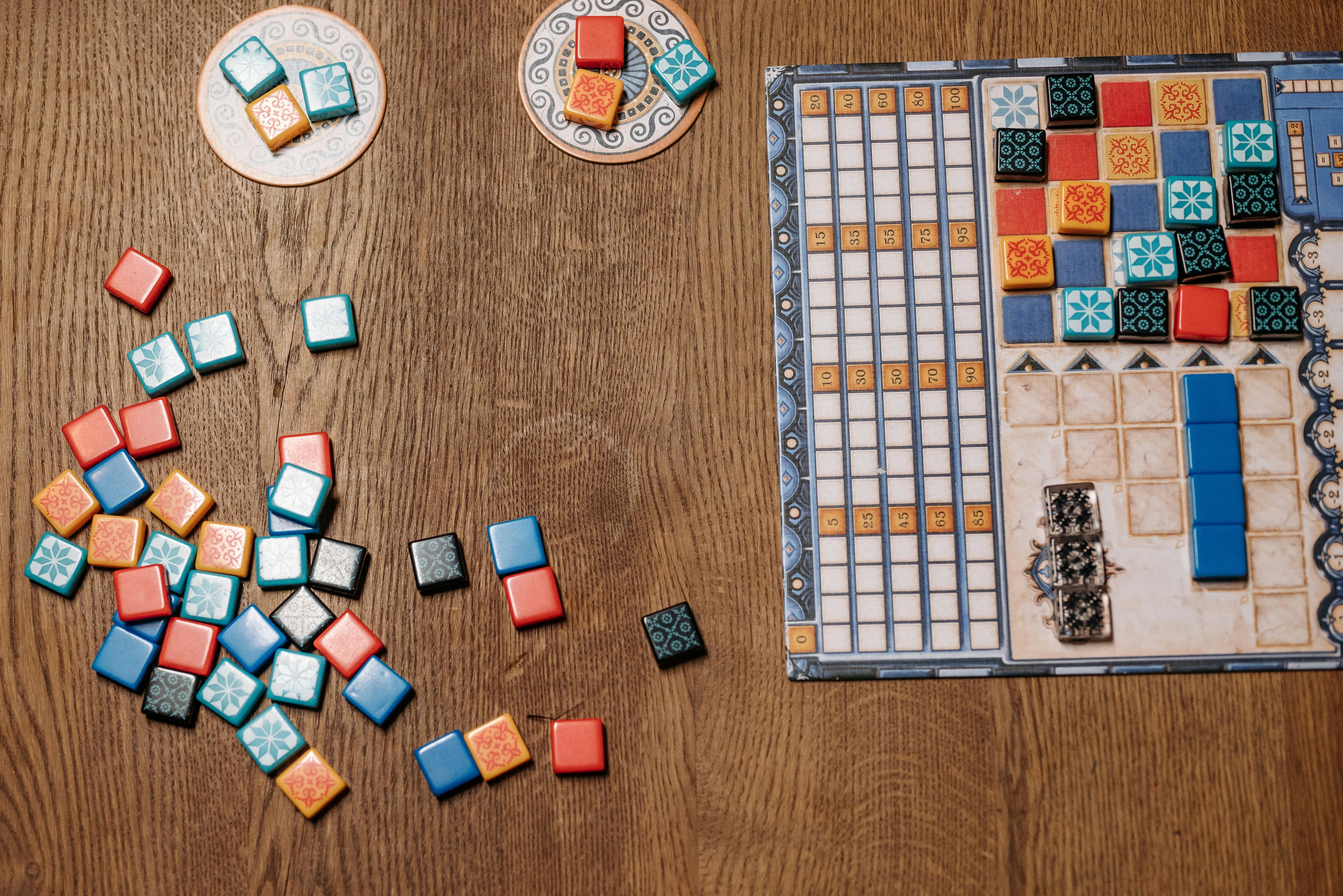 Colorful collection of board game components including dice, meeples, cards, and tokens